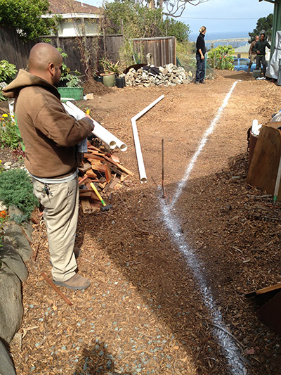 A line of talk cuts through a mulched back yard, identifying where the downspouted rainwater will be directed